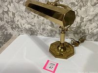 Side view of the vintage brass piano lamp showing the octagonal base and the elongated hexagonal shade along with the power cord.