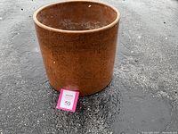 Full side view of mottled brown ceramic planter showing cylindrical shape and weathered surface.