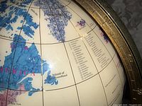 Close-up of globe showing North America and Greenland carved and colored with varied blue and cream gemstones and detailed with country names.