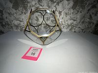 Front and side view of gold framed glass geometric octagon ball sculpture with mirror bottom.