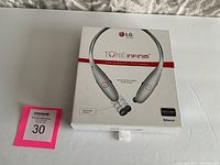LG Tone Infinim HBS-900 Premium Wireless Stereo Headset in sealed retail box placed on white surface next to a MaxSold tag with number 30.