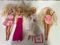 Four older blonde Barbie dolls arranged side-by-side showing their outfits and hair details.