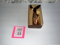 Top view of the rectangular wooden puzzle box showing dark carved eagle clutching American flag with mother of pearl accents.