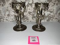 Pair of Studio Silversmiths silver plated candle holders with grapevine design shown side by side on a plain light background.