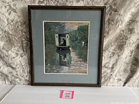 Frontal image of the framed Monet print showing the boat on the water image inside a blue mat and brown wooden frame.