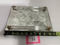 Top down photo of square vanity tray showing floral mirrored base and Lucite rod edges with gold metal corners, with measuring tape indicating approximate width of 10 inches.