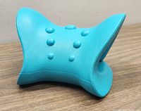 Side view of the elastic blue cervical traction pillow showing its curved design and raised massage nodes.
