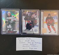 Front of the three rookie trading cards showing Connor Bedard, Macklin Celebrini, Kirill Kaprizov with handwritten note listing names and card highlights