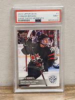 Front of the PSA graded 2023 Upper Deck Connor Bedard Team Canada Game Dated Moments trading card showing player celebrating with hockey stick, PSA grade 9 Mint, certification number 80585200.