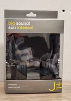 Front packaging showing black J+ stereo headphones with cushioned ear pads, in retail box.
