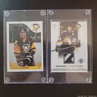 Both trading cards side by side in screw-down holders