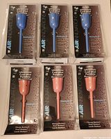 Six new Air Innovations ultrasonic portable humidifiers in original packaging, three blue and three pink, arranged in two rows.