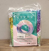 Packaged sequined rainbow swimming ring, 90cm size shown on packaging.