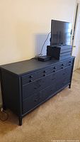 Full side view of the navy blue vintage dresser showing all drawers and legs.