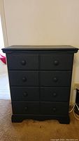 Front view of navy blue hi-boy dresser showing eight drawers and overall condition.