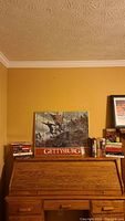 Books and art focused on the Civil War period, with a prominent Gettysburg box or book on top of a wooden roll-top desk.