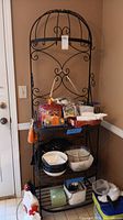 Front view of the full cast metal pan rack with items on shelves and hooks on the upper section