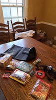 Photo of camping gear spread on a wooden table including dry bags, pedometer, chapstick, safety first aid kit, collapsible cup, cooling wrap, and other items.