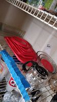 Shelf with red plastic lids stacked on top of Pyrex round glass dishes and five rectangular Pyrex dishes below.