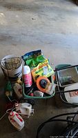 Photo showing Scott's seeder, Turf Builder fertilizer bag, Pest Defense spray, five gallon bucket, metal plant hanger, bird feeder, and other gardening liquids and containers