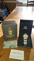 Photo showing the watch inside its black Honda-branded presentation box alongside the outer box with 'President's Award' labeling and accompanying documents.