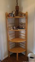 Photo showing the full wooden corner shelf placed in a room corner with various decorative items on the shelves.