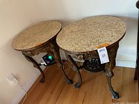 Both tables side by side showing round tops and cast iron bases with decorative details