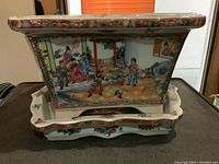 Front view of the trapezoidal porcelain planter on matching underplate showing hand-painted figures in traditional Chinese attire and floral/bird motifs.