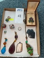 Overview of two sterling rings, two brooches, Haida artwork and assorted pendants in box