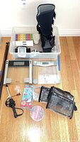 Overview of personal care items and walking sticks arranged on a floor including scales, blood pressure cuffs, pill boxes, curling iron, Sonic Pic, toiletry bags, salt soak jar.