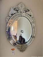 Full front view of an ornate Venetian style oval wall mirror hanging on a wall