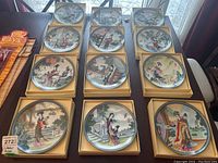Twelve decorative porcelain plates in original fitted boxes arranged 3×4 on a table