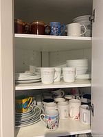 Shelves of assorted ceramic mugs, plates, and bowls with varied patterns and solid colors.