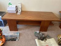 Front view of teak coffee table with various items on top, showing overall design and two solid legs