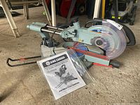 Overall view of the saw and instruction manual on concrete floor