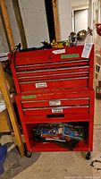 Red two-piece metal tool cart with top chest and rolling base on casters