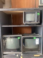 Three CRT displays on shelving: two 16" Sony Trinitron TVs on lower shelf and one 8" Sony SV-81000 color monitor on upper shelf