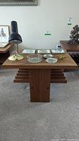 Front view of the teak side table showing top surface with various decorative items and lower shelf details.