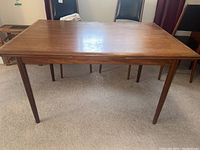 Full side view of teak dining table showing tabletop surface, tapered legs and overall profile