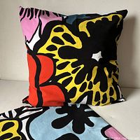 Front view of one Marimekko cushion cover stuffed for display showing large floral patterns in bright colors with bold black outlines.