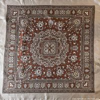 Overall view of a square vintage scarf laid flat showing full design in brown, cream, and beige with intricate paisley and floral pattern.