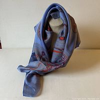 Scarf displayed draped over a stand showing its drape and fabric texture.