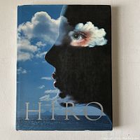 Front view of the book with dust jacket showing surreal image combining profile of a face with clouds and sea, title HIRO in large letters.