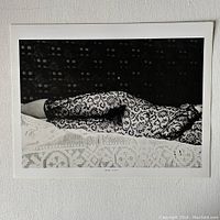 Front image of the print titled "The Kiss" showing a black and white photograph of a reclining figure in lace-patterned stockings.