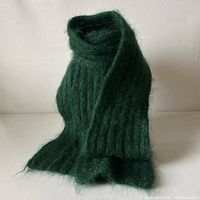 Scarf displayed folded in standing position showing its ribbed texture and fuzzy mohair-like surface.