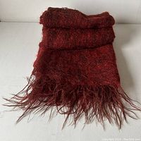Folded red mohair and wool throw with fringed edges, showing texture and softness of fabric.