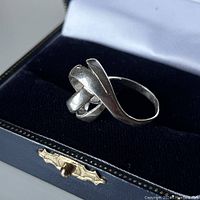 Sterling silver ring resting in a dark blue velvet jewelry box with gold-tone hinge detail.