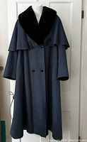 Front view of navy blue full-length wool coat with black fur collar and double leather buttons, displayed on mannequin.