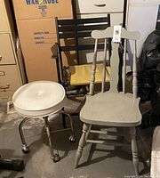 Three chairs together: white vinyl stool with chrome legs, black wooden folding chair with yellow cushion, and grey wooden spindle back chair.