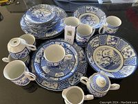 Set of multiple pieces including flat cups and saucers, dinner, salad, soup plates, mugs, sugar bowl, creamer, and vegetable bowl all with blue and white Oriental Garden pattern by Gumps.